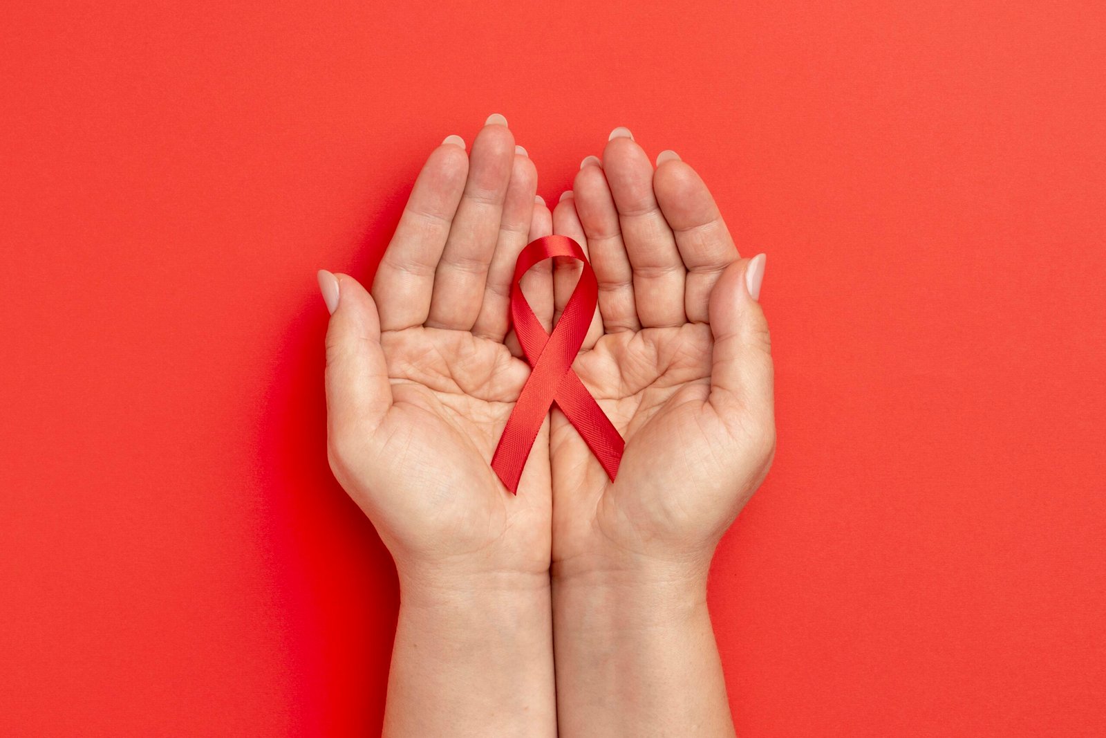 Mãos segurando o laço vermelho: Conscientização sobre a Aids